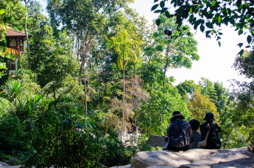 Grupa ludzi siedzi na skale w świątyni niedaleko Chiang Mai. 