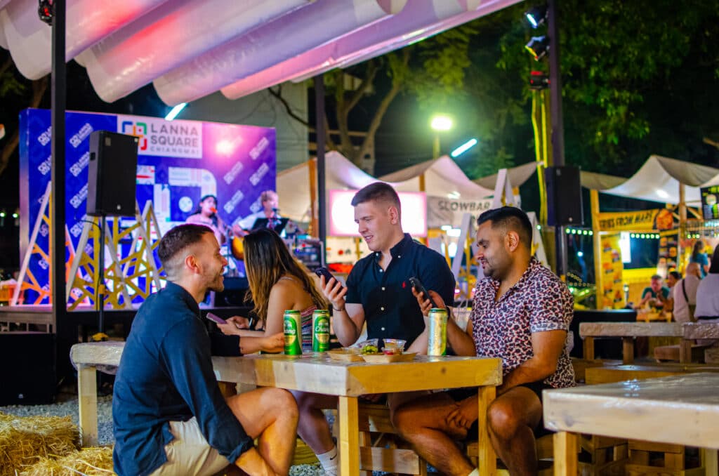 A group of male tourists sitting at a table at a night market in Chiang Mai.